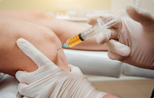 A gloved medical professional injecting a yellow liquid (likely regenerative therapy) into the knee of a patient.